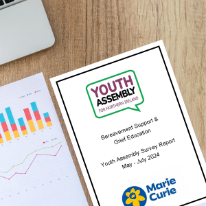 A desk with the edge of a laptop in view in the top left corner. On the desk are two pages of a report. One page shows random graphs and tables. The other page is the title page of the Youth Assembly's bereavement report.