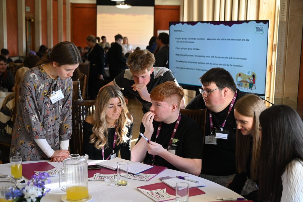 Six youth assembly members working together at a table